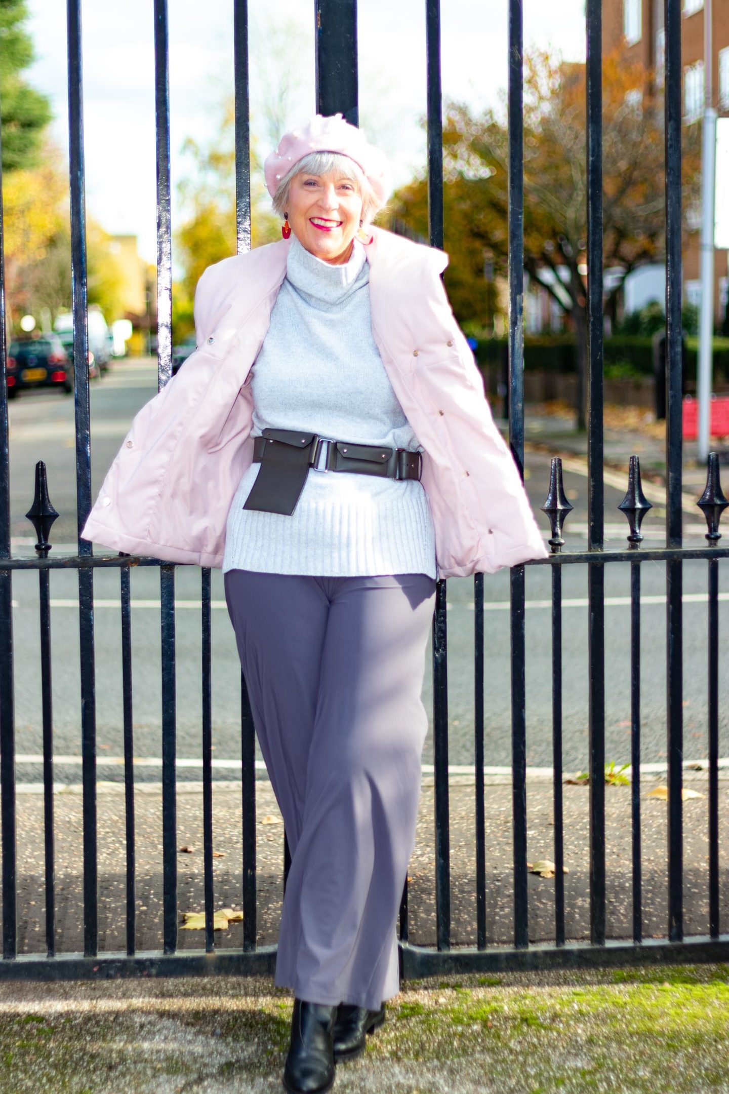 pink puffer jacket, grey sweater and grey trousers