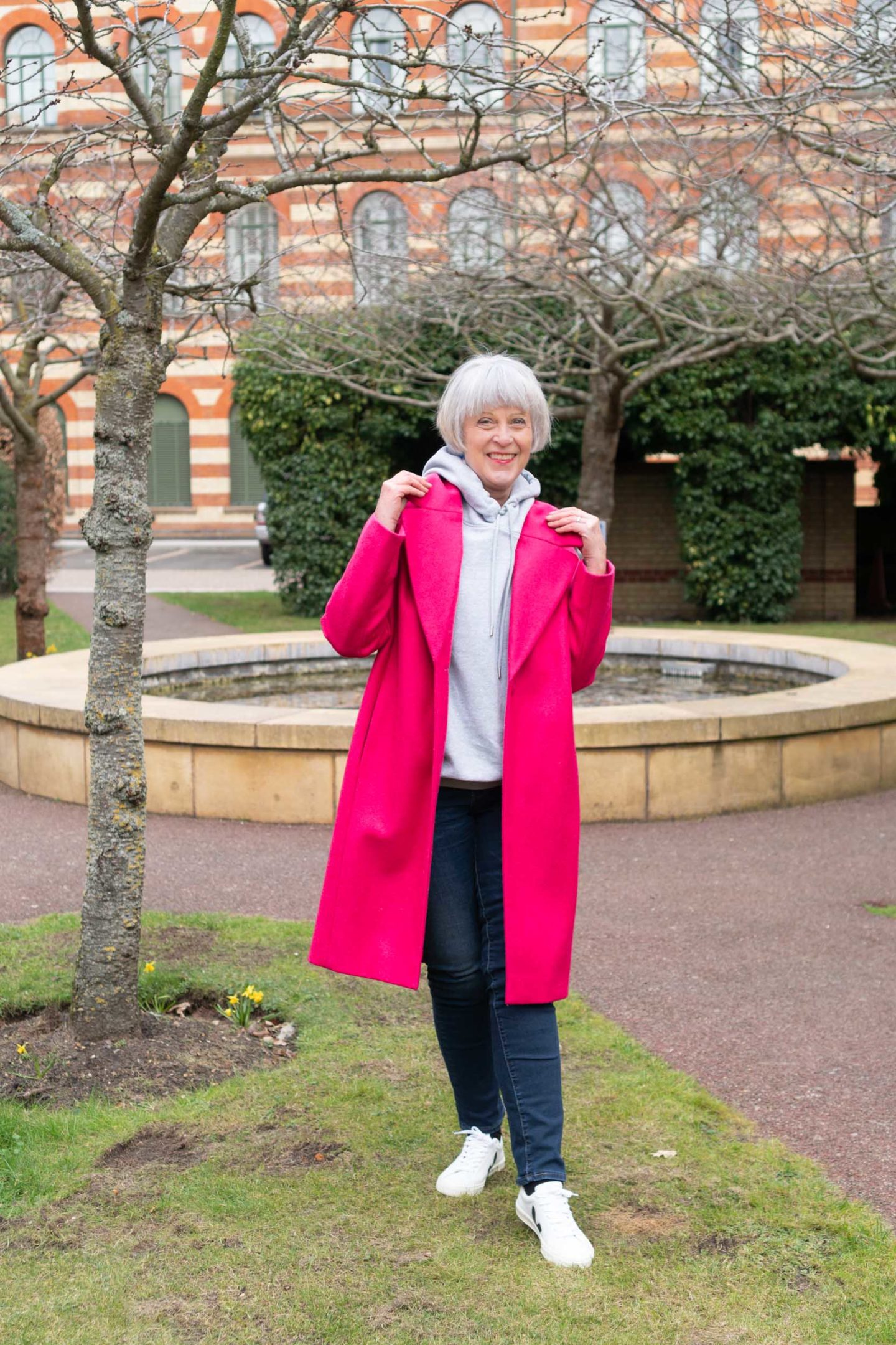 Bright pink coat, grey hoodie and jeans.