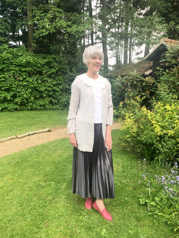 Grey pleated skirt, grey cardigan and write tee.