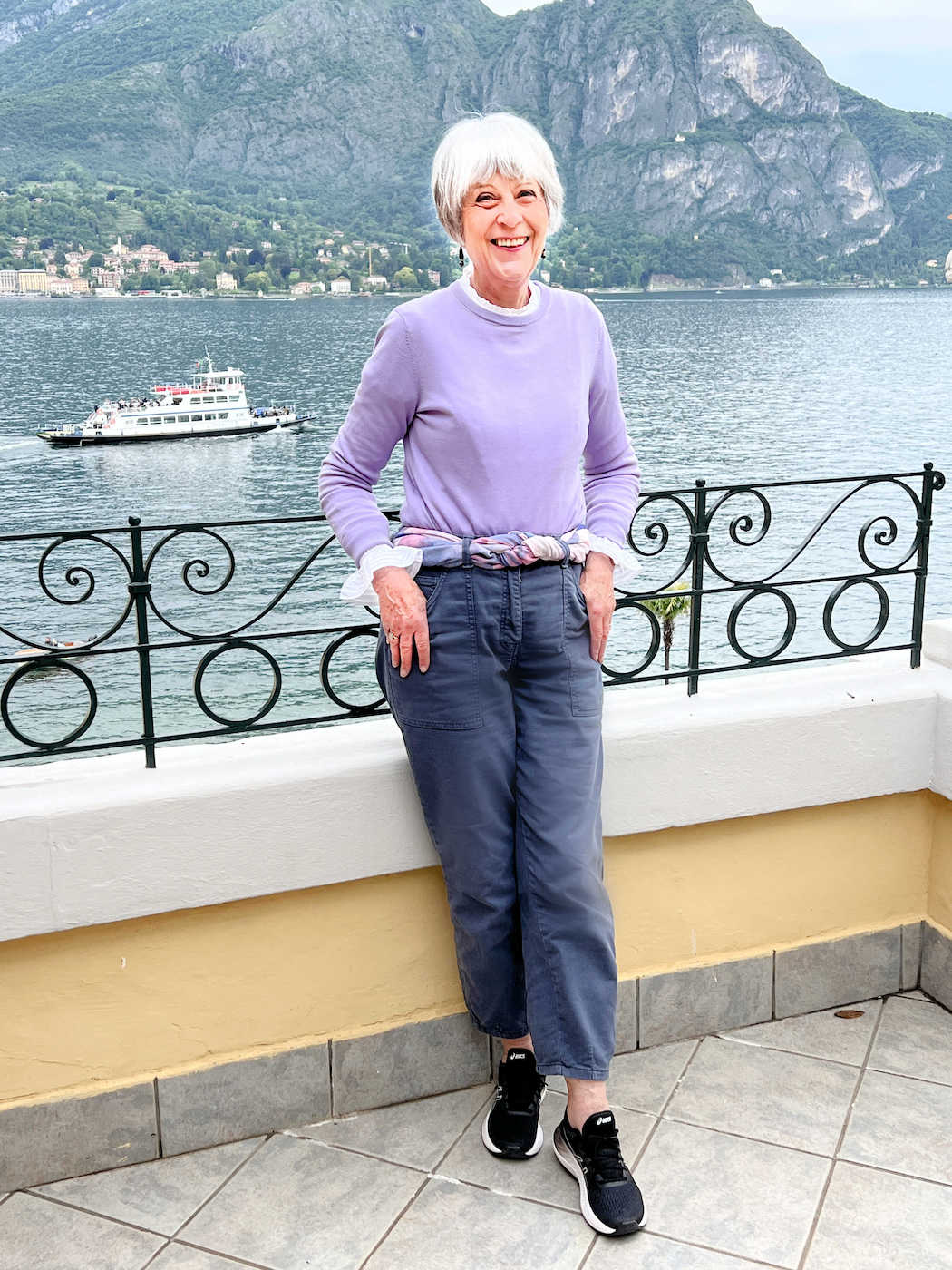 Lilac sweater and grey trousers on the balcony at Villa Serbelloni. 